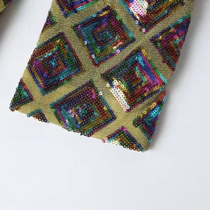 Men fashion sequin suit jacket detail close-up, gold metallic fabric with colorful geometric diamond pattern.