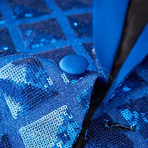 Close-up detail of blue sequin men's blazer fabric, lapel collar, and matching fabric button.