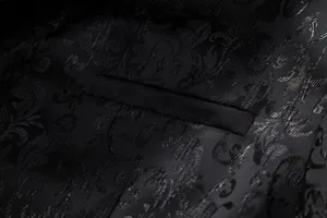 Detailed view of black jacquard men's suit jacket fabric and pocket craftsmanship.