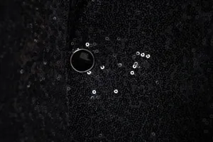 Men's sequin suit jacket fabric detail showing sparkling black paillette design.