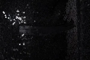 Close-up of black sequin blazer pocket detail, shining men suit fabric texture.