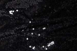 Black sequin fabric texture detail close-up for men shiny evening jacket and party suit.