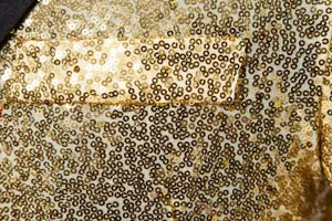 Detailed close-up view of a luxurious men's gold sequin blazer, showcasing sparkling texture.