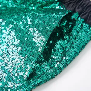 Primo piano sul dettaglio dei pantaloni da uomo in tessuto di paillettes verdi ed elastico.