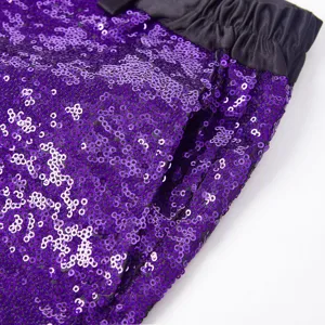 Dettaglio dei pantaloni di paillettes viola da uomo con tessuto scintillante e cintura nera.