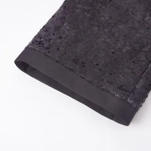 Primo piano del risvolto di pantaloni con paillettes scure e finiture in raso nero, elegante.