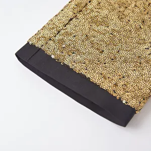 Vista dettagliata dell'orlo dei pantaloni eleganti con paillettes dorate e bordo nero.