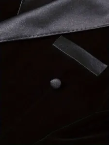 Close-up detail of black velvet men suit blazer lapel button texture fashion style