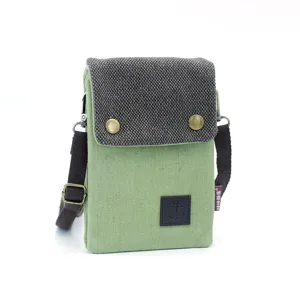 Canvas phone bag detail shot showing textured flap, metal snap button, and anchor logo.