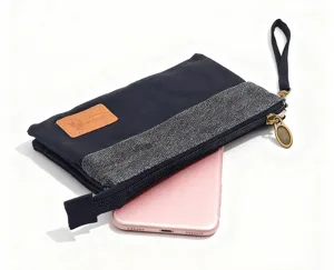 Gros plan detail du sac clutch en toile multi couches avec etiquette cuir et fermeture éclair.