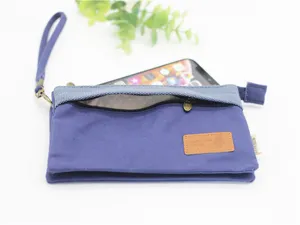 Gros-plan sac pochette multi-couches en toile avec poche zippée et dragonne détail.