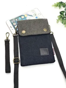 Denim cell phone crossbody bag with canvas flap, metal buckle, adjustable strap detail.