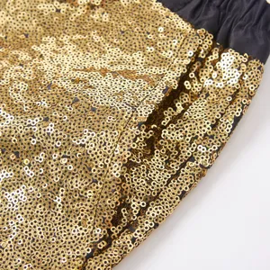 Primo piano dettagliato del tessuto dei pantaloni con paillettes dorate, superficie brillante.