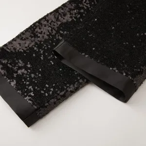 Primo piano dettaglio di pantaloni da uomo con paillettes nere e finiture in raso lucido.