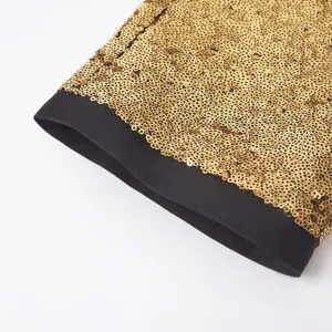 Primo piano dettagliato di paillettes dorate lucide con orlo a contrasto nero sui pantaloni.