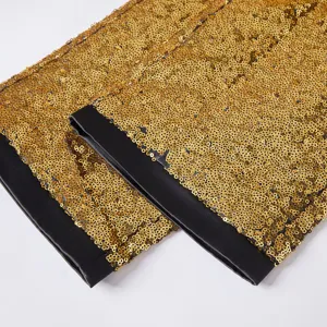 Dettaglio pantaloni da abito con paillettes dorate da uomo, polsini neri da spettacolo.