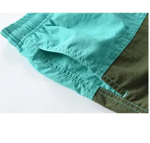 Gros-plan sur le short de bain color-block pour homme, avec taille élastique et poches contrastées.