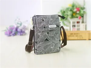 Detailed view of the black and white leaf print crossbody phone bag with brown strap.