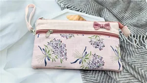 Dettaglio della borsa da polso in tessuto floreale rustico, con doppie zip e fiocco decorativo.