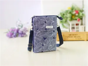 Blue floral print fabric crossbody phone bag detail showing handmade tag and leaf pattern.