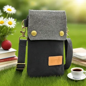 Detailed view of grey canvas crossbody phone bag featuring brass hardware in outdoor setting.