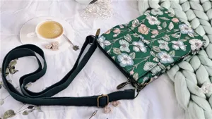 Detailed view of the green floral fabric crossbody phone bag, showing multi-layer pocket.