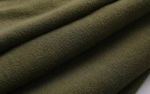 Primo piano dettagliato in tessuto pile verde oliva con consistenza morbida e pieghe.