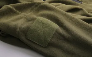 Primo piano sul dettaglio della manica della felpa tattica in pile con pannello in velcro.