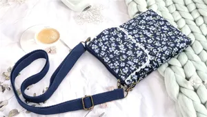 Charming floral crossbody phone bag detail featuring blue fabric, lace trim, and adjustable strap.
