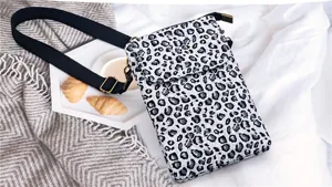 Chic black and white leopard print crossbody phone bag with adjustable black strap, ideal for daily use.