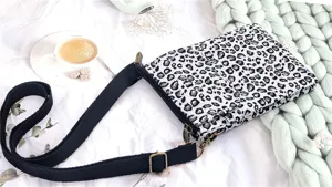 Canvas crossbody phone bag with chic black and white leopard print and adjustable strap.