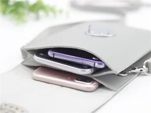 Primo piano dettagliato della borsa a tracolla in ecopelle grigia che contiene più smartphone.