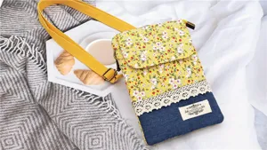 Floral denim cross-body phone bag with lace trim and yellow strap for daily casual use.
