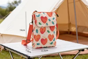 Canvas phone crossbody bag detail showing size dimensions, red heart print, and outdoor camping scene.