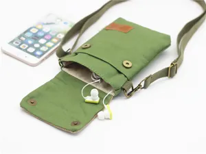 Detail view of green canvas crossbody phone bag featuring adjustable strap and metal snap buttons.