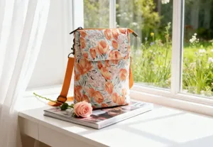 Floral fabric crossbody phone bag detail showing pastoral print and orange strap.