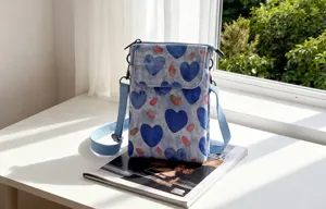 Detail view of a blue fabric crossbody phone bag with cute heart pattern and adjustable strap.