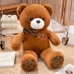 Brown teddy bear plush toy detail showing soft fabric texture, cute check bow and heart patch.
