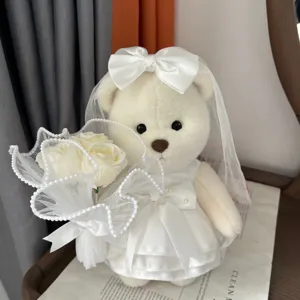 White wedding plush bear doll detail view, wearing lace veil and dress holding flower bouquet.