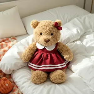 Plush teddy bear wearing red dress detail view in cozy bedroom. Stuffed toy scene.