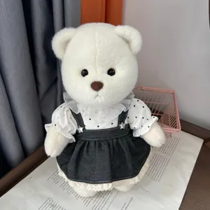 Plush teddy bear doll wearing cute white polka dot blouse and dark denim skirt set detail.
