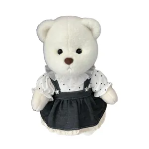 White plush teddy bear doll wearing a polka dot blouse and denim suspender skirt set