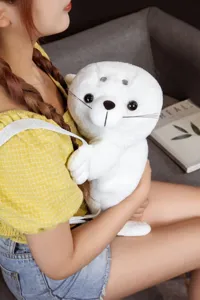 Primo piano di un simpatico zaino di peluche foca bianca indossato da una modella, morbido.