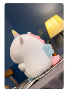 Cute unicorn plush toy detail view, fluffy white stuffed animal with rainbow horn and wings.