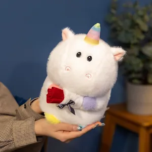 Close-up detail of a cute white unicorn plush toy holding a red rose in a cozy room setting.