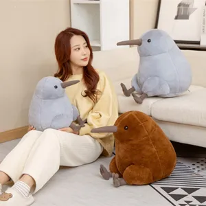 Lifestyle detail shot featuring cute kiwi bird plush toys with model on cozy living room sofa.