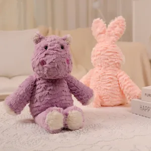 Primer plano detallado de adorables peluches de hipopótamo morado y conejo rosa.