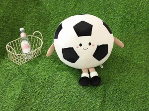 Detailaufnahme des niedlichen Cartoon Fußball Plüschkissens mit gesticktem Gesicht auf Rasen.