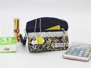 Floral denim coin purse detail showing double zippers, lace trim and handy wrist strap.