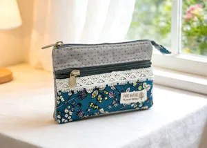 Detail view of multi-layer floral fabric coin pouch with lace trim and metal zipper.